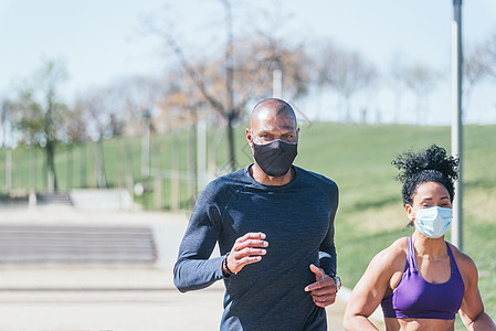 男人运动戴面具的男人和女人在公园里跑来跑去背景