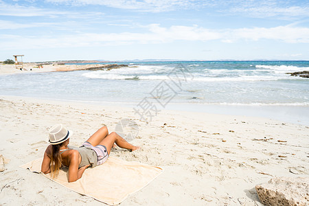 晒日光浴在海滩上做日光浴的漂亮女人 西班牙福门多岛身体晴天娱乐蓝色长发女性水平假期黑发享受背景