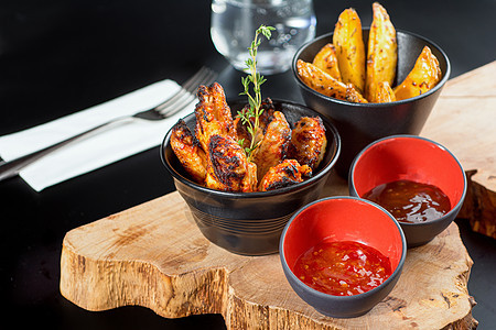 BBQ鸡翅 配有酱汁和薯条 木质餐具的缝合带选择性焦点图片