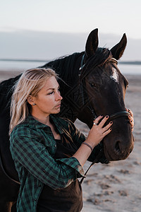 金发女郎骑着拥抱马 美丽的黑种马女士享受日落的自然 爱与友谊的概念 笑声动物草地天空牧场农场自由跑步家畜行动摄影图片