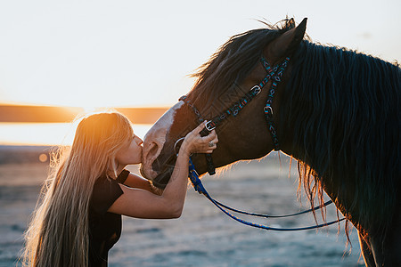 金发女郎骑着拥抱马 美丽的黑种马女士享受日落的自然 爱与友谊的概念 笑声行动农场宠物草地自由家畜鬃毛动物速度哺乳动物图片