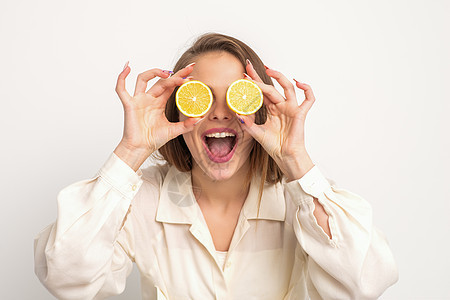 持有两片橙子的妇女水果微笑头发成人女孩温泉饮食化妆品乐趣眼睛图片