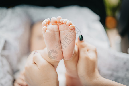 母亲亲手握着小婴儿男孩的脚 新生儿概念父母毯子新生男生童年皮肤压痛棕榈脚趾家庭图片