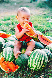 穿着滑稽服装的快乐小男孩坐在田野或花园里吃西瓜片 快乐的婴儿孩子微笑 孩子在户外吃水果公园营养后院幸福裙子童年晴天乐趣食物卷曲图片
