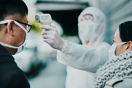 医护人员在机场或边境测试 covid 温度以了解协议 合规性或国家/地区限制 在检疫或电晕病毒筛查中戴面罩的外国旅游者图片