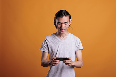 亚裔青少年在电话上玩电子游戏图片