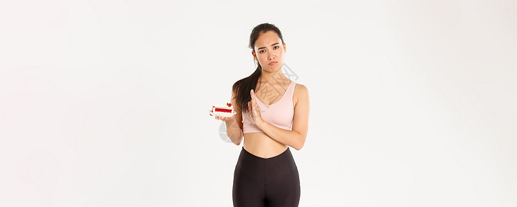 积极的生活方式 健身和幸福理念 坚定的亚洲女运动员拒绝甜食 在节食期间戒掉垃圾食品 减肥 拒绝吃蛋糕 站在不情愿的白人背景下肌肉图片