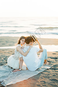 女人坐在沙滩上时拥抱男人肩膀图片