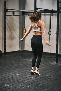 在健身房跳过绳子的年轻女子 跑到健身房去图片