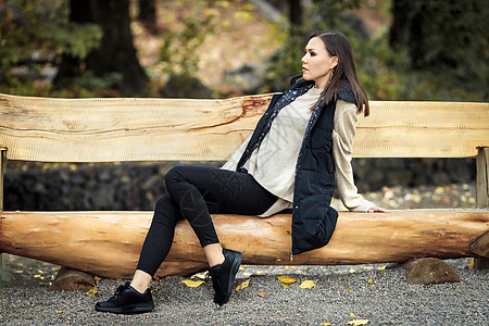 一名处于全面成长期的年轻妇女坐在户外公园木板凳上的情况简介图片