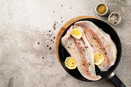 以混凝土为背景的煎锅中含有柠檬和香料的原泛马西休鱼片平底锅市场食物动物鲶鱼营养美食鱼片海鲜烹饪图片