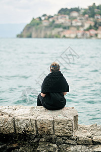 一个女孩坐在马其顿湖边 欣赏着奥赫里德老城的景色 从后面看一看房子女孩女性女士城市历史性建筑晴天天空游客图片