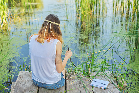 年轻女士坐在木码头 复制空间上与她的背部坐在一起图片