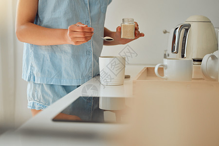 早上在厨房里准备一杯咖啡 茶或热巧克力时 随便的女人加糖 女手拿着茶匙在杯子里喝新鲜饮料 在家吃早餐图片