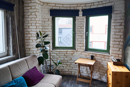 设计一个有灰色沙发 植物 木制桌 抽屉箱和海湾窗户的房间图片