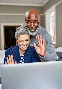 一位年长的夫妇挥手 在家用视频聊天他们的笔记本电脑 (笑声)图片