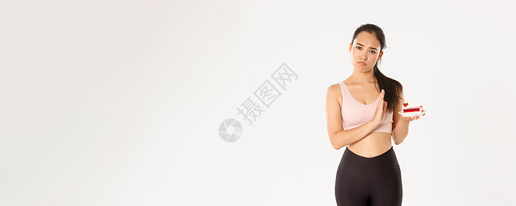 积极的生活方式 健身和幸福理念 坚定的亚洲女运动员拒绝甜食 在节食期间戒掉垃圾食品 减肥 拒绝吃蛋糕 站在不情愿的白人背景下健美图片