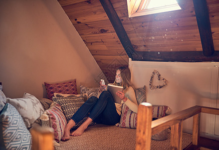 一个年轻女人在智能手机上发短信 在家里的卧室里放松一下 在她家房间休息时图片