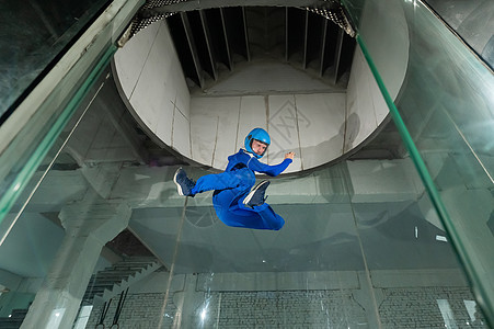 身穿制服和戴防护头盔的人喜欢在风道飞行 自由坠落模拟器飞点溪流身体闲暇管子悬浮隧道爱好吸引力航空图片