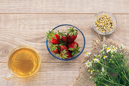 一杯绿茶 白甘菊花的石莓 木制背景上玻璃杯子洋甘菊草本植物食物药品饮食早餐植物母菊图片