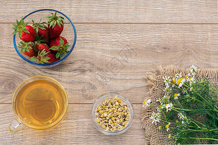 一杯绿茶 白甘菊花的石莓 木制背景上杯子药品食物饮食植物母菊玻璃洋甘菊草本植物早餐图片