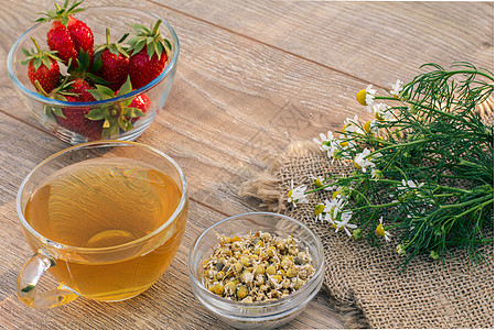 一杯绿茶 白甘菊花的石莓 木制背景上饮食植物母菊杯子早餐草本植物药品玻璃洋甘菊食物图片