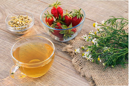 一杯绿茶 白甘菊花的石莓 木制背景上草本植物玻璃洋甘菊饮食母菊植物食物早餐杯子药品图片