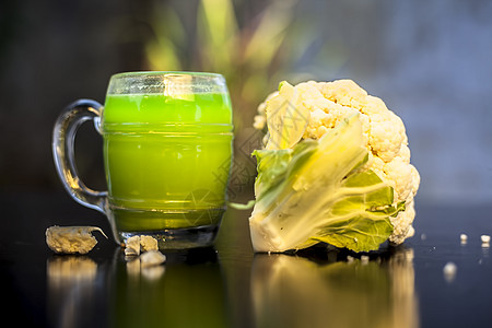 近距离拍摄生菜花及其健康的果汁 在黑色表面的玻璃杯中 有选择性地聚焦 有创意的照明和模糊的背景叶子豆芽菜花排毒流质饮食环境营养奶图片