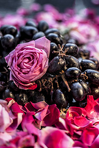 近距离拍到一帮新鲜的生葡萄 还有红花和粉红色玫瑰花 还有黑木板上的花收藏软木玫瑰灌木花瓣周年藤蔓栽培乡愁花瓶图片