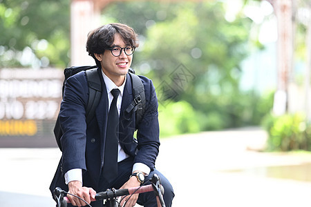 年轻商务人士在城市街道上骑自行车微笑着图片