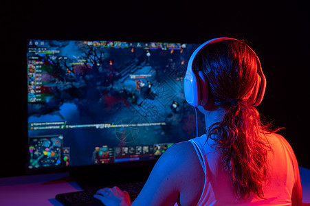 一名白人女性在黑暗中在霓虹灯下玩电脑游戏的后视图锦标赛喜悦技术电脑老鼠比赛键盘娱乐竞赛游戏图片