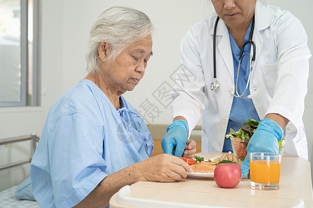 亚洲年长或年长的老妇人病人坐在医院的床上饿着肚子吃早餐和蔬菜健康食品 充满希望和快乐女士手术食物诊所营养退休女性药品男人医生图片