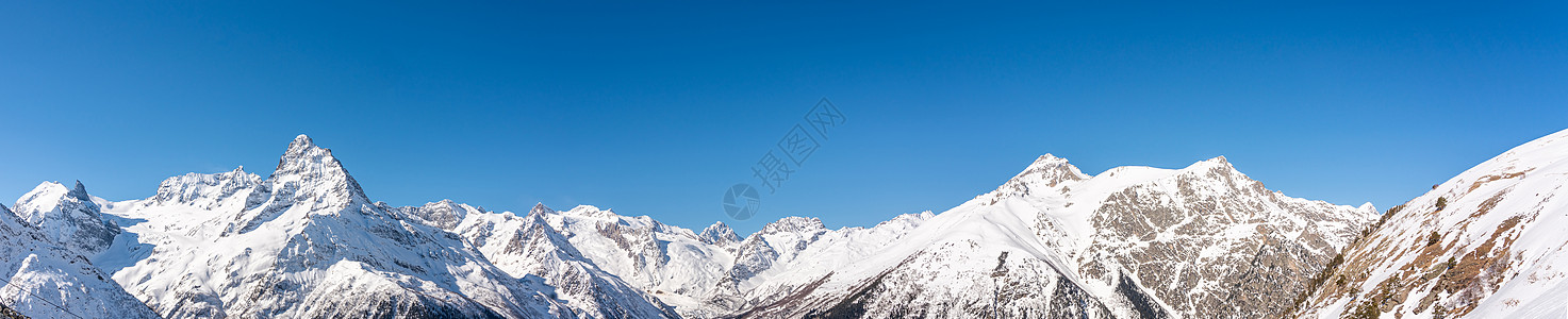 俄罗斯高加索地区蓝色天空的冬季雪山 风景全天观 俄罗斯晴天岩石顶峰山脉天际山链高山山峰地平线全景图片