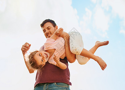 这个家庭知道如何玩得开心 一个快乐的小女孩和她父亲在家里后院一起玩耍的肖像图片