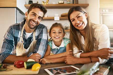 对食物的热爱在这个家庭中蔓延 两个快乐的父母和他们年幼的女儿一起在厨房里尝试新食谱的肖像图片