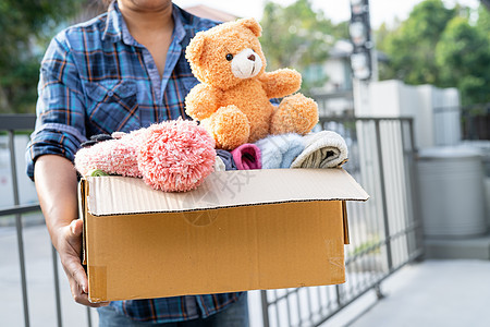 在家里拿着装有旧衣服和洋娃娃的衣物捐赠箱 支持帮助世界上的穷人包装机构衣柜比例服装福利送货头脑娃娃玩具图片