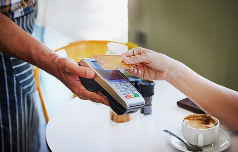 支付就像点击一样简单 一位身份不明的年轻女子在咖啡店使用她的信用卡支付咖啡费用背景图片