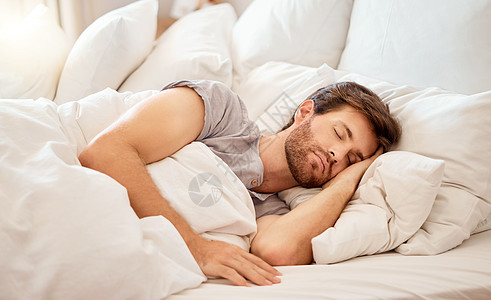 一个疲惫的男人睡在家里的卧室床上 放松 睡眠和安宁 早上在他家的枕头上闭着眼睛做梦 放松和休息 冷静迷人的人小睡图片