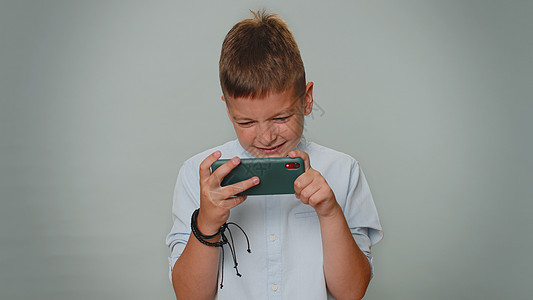 充满激情地在手机上玩赛车游戏游戏的青少年儿童童(Teddler男孩)图片