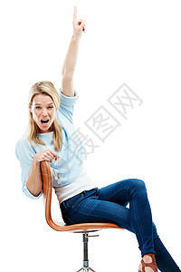 一位坐在椅子上 站在白色背景下向上指的年轻女子的摄影棚肖像画 你看到了吗?图片