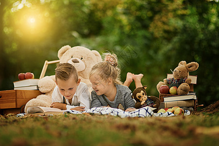 公园是他们玩耍的好地方 一个小男孩和他妹妹在树林里读书了图片