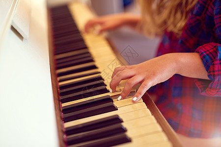 她的音乐技艺越来越强了 一个年轻女孩弹钢琴的近距离镜头图片