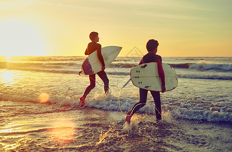 哪里有意志 哪里就有浪潮 两个年轻的兄弟拿着冲浪板涉水入海图片