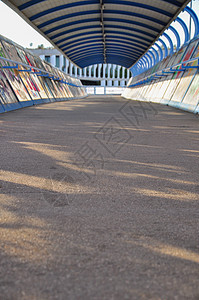带有涂鸦的城市廊桥 走道沥青地板上的日落光线和阴影背景图片