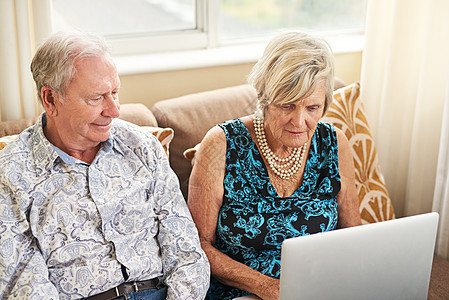 离家近 与外界相距甚远 一个年老夫妇在家里沙发上用笔记本电脑在一起图片