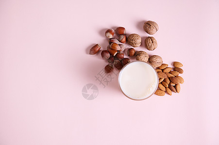 以奶为原料的健康的营养素生素植物平板玻璃 以及粉红色背景的坚果组合 (拷贝广告空间)背景图片