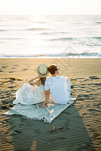戴帽子的女人坐在沙滩上 靠着一个男人的肩膀图片