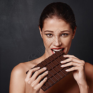 我不能对巧克力说不 演播室拍到一个迷人的年轻女人咬着一块巧克力板图片