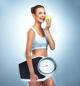 健康是90饮食 一位注重健康的年轻女子在工作室里摆着苹果和体重秤的画像图片