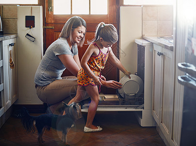 母亲和女儿在家用洗碗机帮她做家务 从小到大都帮她做杂务工作图片